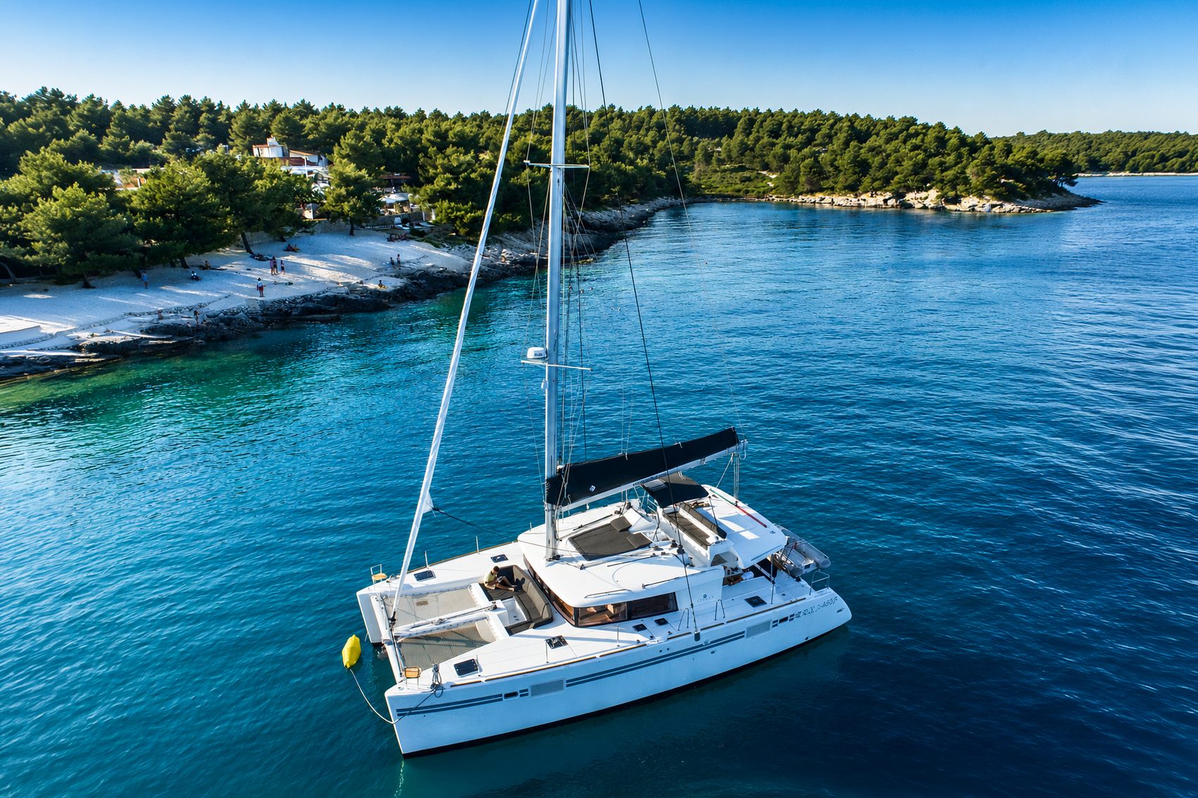 Quicon, a Lagoon 450 sailing catamaran, anchored in a clear-water cove